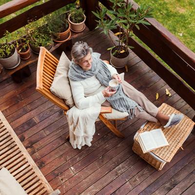Top view of an elderly woman with a book while sitting relaxingly by her home's terrace.