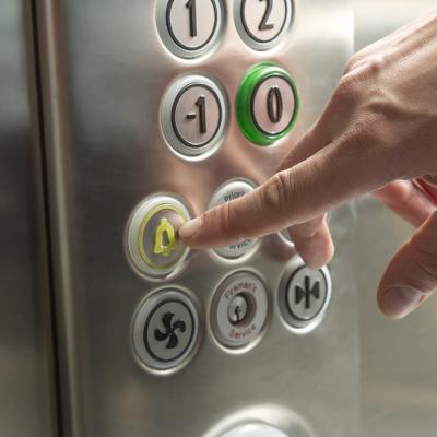 A person's hand pressing the alarm button in the elevator.