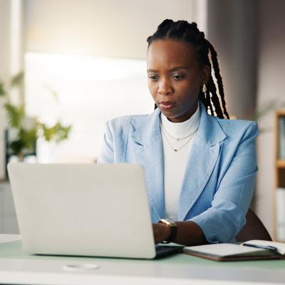 An office employee proofreading a work task before publication from her laptop.