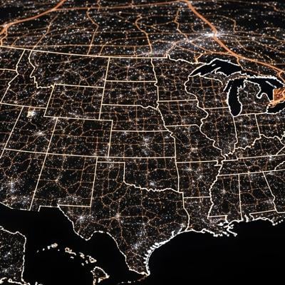 A view of the United States of America at night, highlighted by city lights.