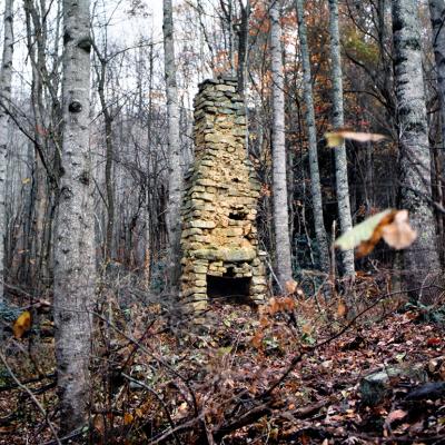 A stone chimney is seen from a 19th century log cabin located in the Appalachian Mountains in Northern America.