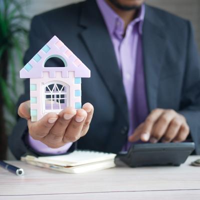 A finance professional holding a small figure of a house as a concept of investing in real estate.