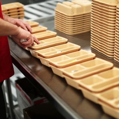 An inmate at Maine Correctional Center in Windham adds condiments to food trays in preparation for distribution throughout the facility. 