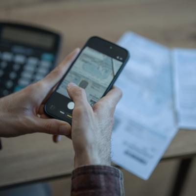 Person holding a smartphone to scan financial documents.