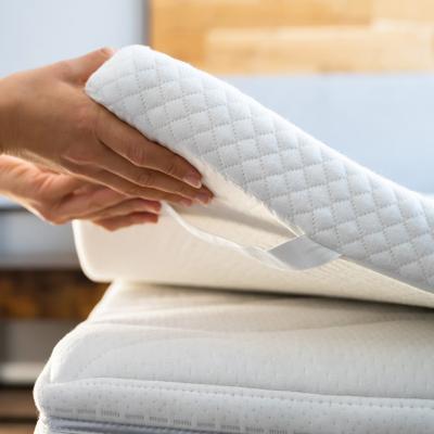 A mattress topper being put on top of a bed. 