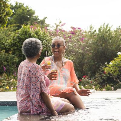 Two retired women having drinks and enjoying their time in a pool.