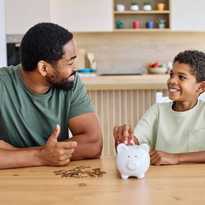 A father teaching his young son to save money in a piggy bank.
