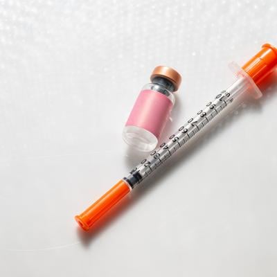Vial of an injectable compound next to a syringe.