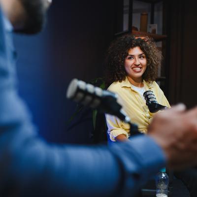 Two podcast hosts happily engaging in discussion for their recording session.