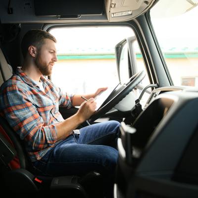 A driver checking cargo documents inside a truck before transportation.