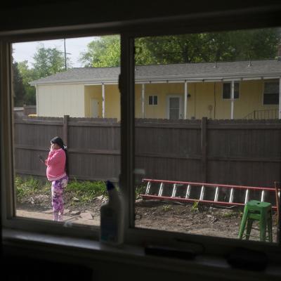 A pregnant woman standing in the backyard of her rental home in Denver, USA while using a smartphone to call her husband in Venezuela.