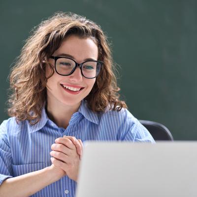 A teacher looking excited while reading good news online.