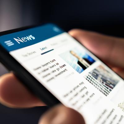 A person reading headlines from a news website online in his smartphone.