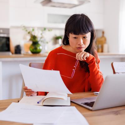 An anxious woman reviewing her bills at home.