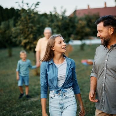 A teenager sharing stories with her father, while walking in the backyard with the family.