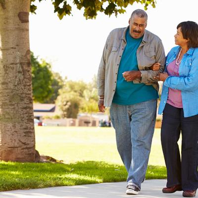 An elderly couple walking together in a park.