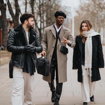 A group of stylish young entrepreneurs walking together outdoors engaged in a conversation.