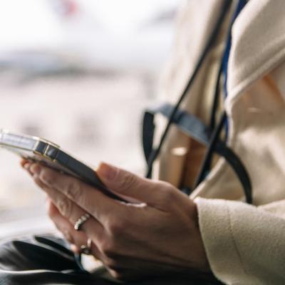 A person checking flight details from her smartphone in the airport.