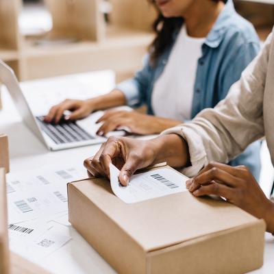 A store owner sticking a barcode label into a package box in an office warehouse.