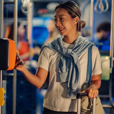 A female tourist paying for bus fare using smartphone NFC technology