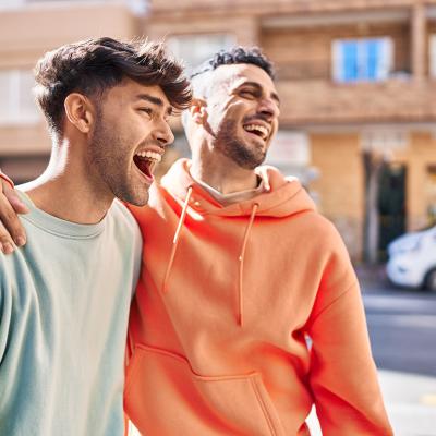 Friends enjoying a good time while side hugging each other outdoors.