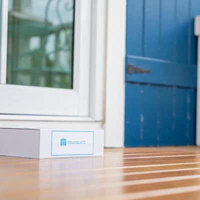 A package box labeled from pharmacy left on the front porch of a house as a delivery.
