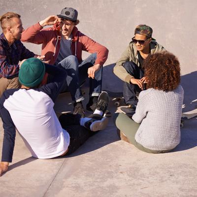 A group of adult skaters hanging out under the sun in a skate park.