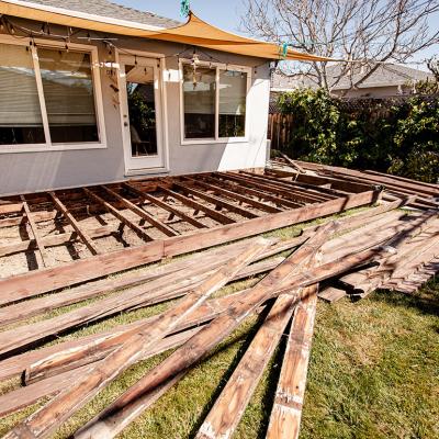 A pile of broken and old wooden lumber laying on the lawn backyard.