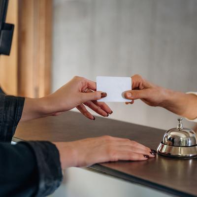 A professional handing credit card over to hotel receptionist to check in.