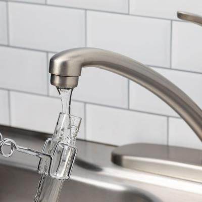 A tube test placed under the tap to collect a water sample from a kitchen faucet.