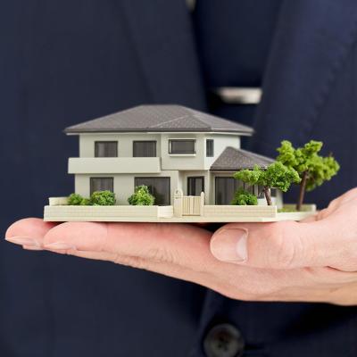 A businessman holding a small-scale figure of a house.
