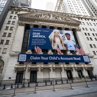The New York Stock Exchange's facade draped with Invest America | Trump Accounts promotional banners across the building.