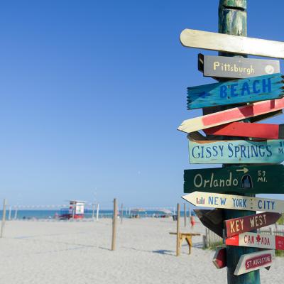 Decorative directional signs displayed from a post in the beach. 