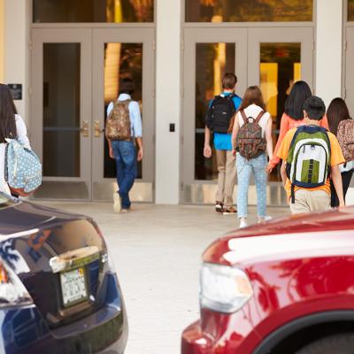 High school students being dropped off by their parents at their campus' entrance.