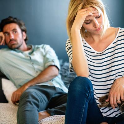 A stressed couple sitting in their living room while the mother comforts her young child.