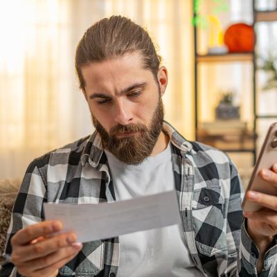A young man reviewing and calculating bills at home.