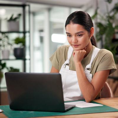A female small business owner using a laptop to review files.