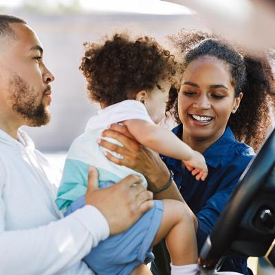 A mother taking her son out of the car during a stop in their road trip.