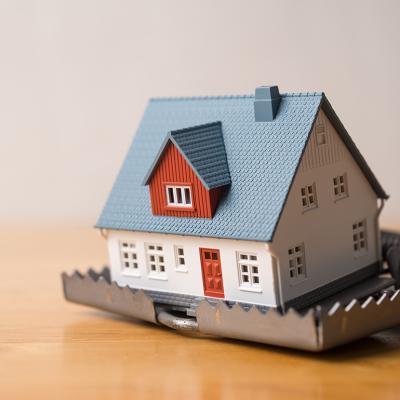 A miniature house within a mouse trap placed in a wooden table.