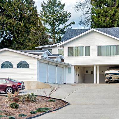 A family house with a private car and a small boat on trailer parked under the carport.