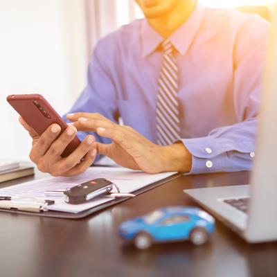 A car dealer calculating monthly car payments for customers from a smartphone.