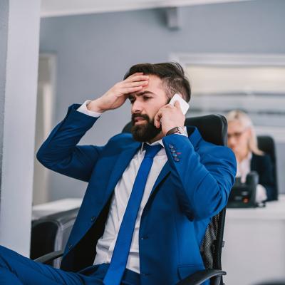 A business manager appearing to be frustrated during a phone call with a client. 