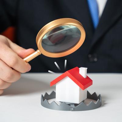 A lawyer examining a figure of a house enclosed in a trap as a concept of illegal property schemes.