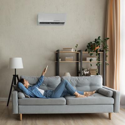 A young woman at home relaxing on the sofa and turning up the AC temperature.