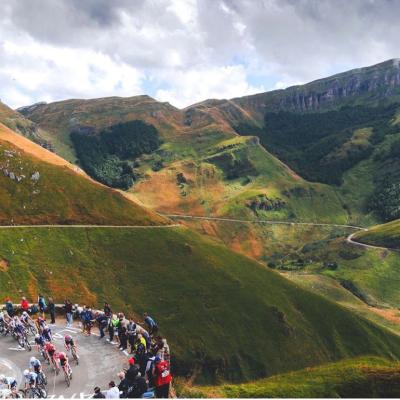 Cyclists descending from a mountain route, with spectators lining up the steep to watch them.