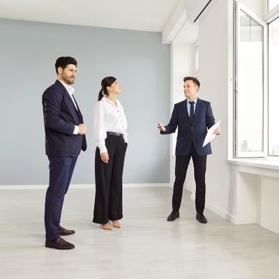 A real estate agent showing an empty and new apartment to a married couple.