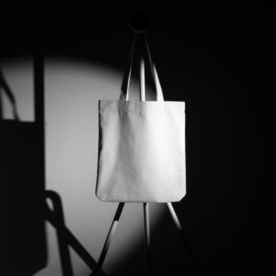 A mockup template of a tote bag on a metal hanger taken in a photo studio.