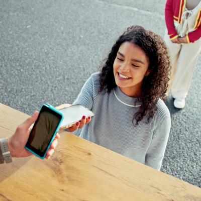 A young woman paying for her food at a food truck using cashless phone payment.