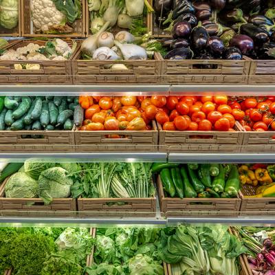 Various kinds of vegetables displayed on boxes in a greengrocer's shop.