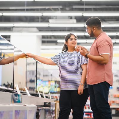 A young couple at an appliance store contemplating to buy a new flatscreen TV.